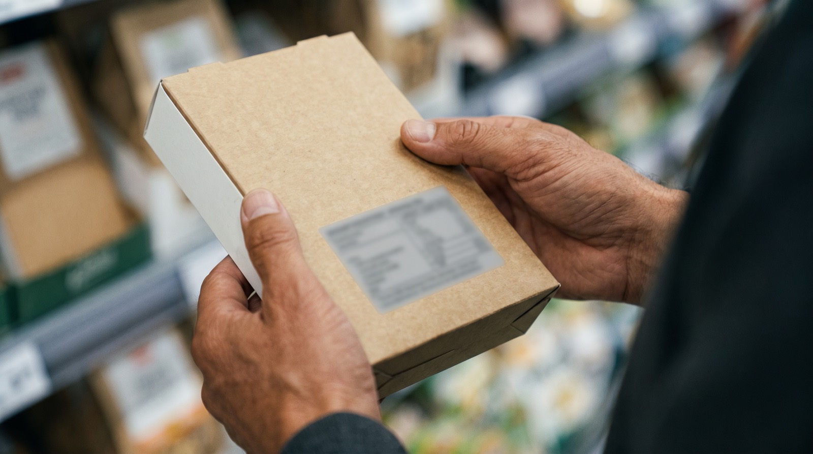 A shopper turning a packet over to read the back-of-pack ingredients panel in a supermarket aisle